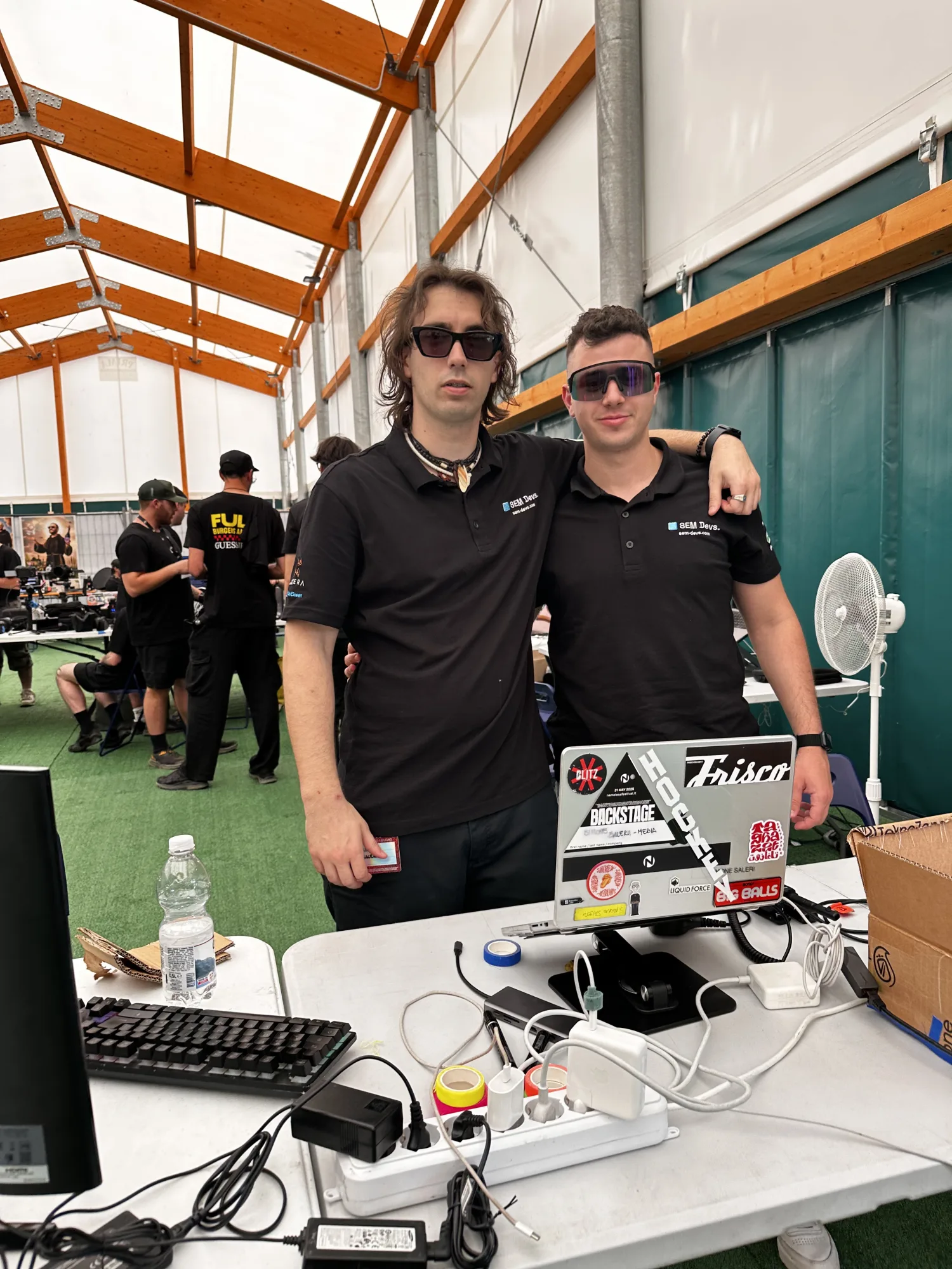 Due tecnici SEM Devs alla postazione di data management del Nameless 2026, con laptop e workstation nel tendone della media crew.